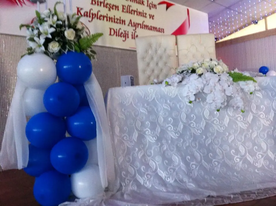 Davet masasının yanında mavi-beyaz balon sütun ve çiçek