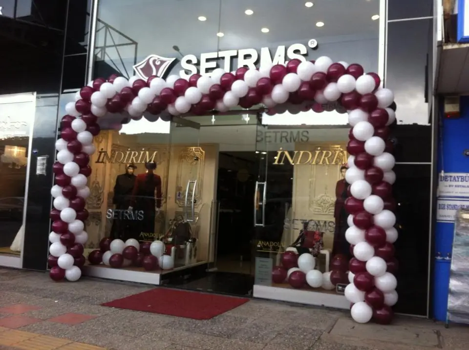 Mağaza girişinde bordo-beyaz spiral balon kemer ve kırmızı halı